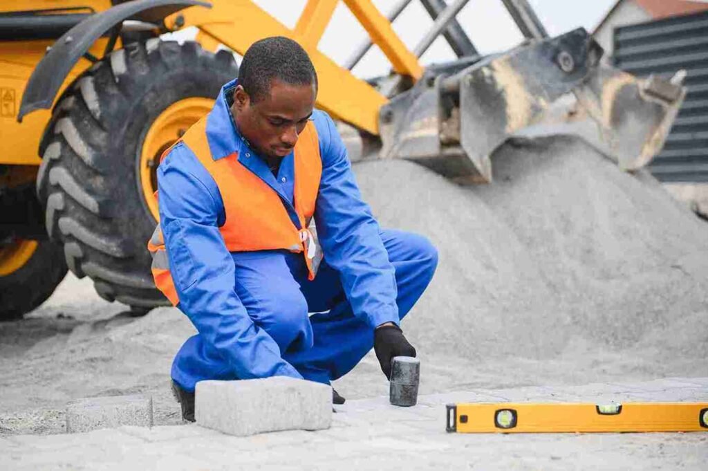 Construction worker installing concrete pavers with precision at a residential job site in Brunswick OH.

